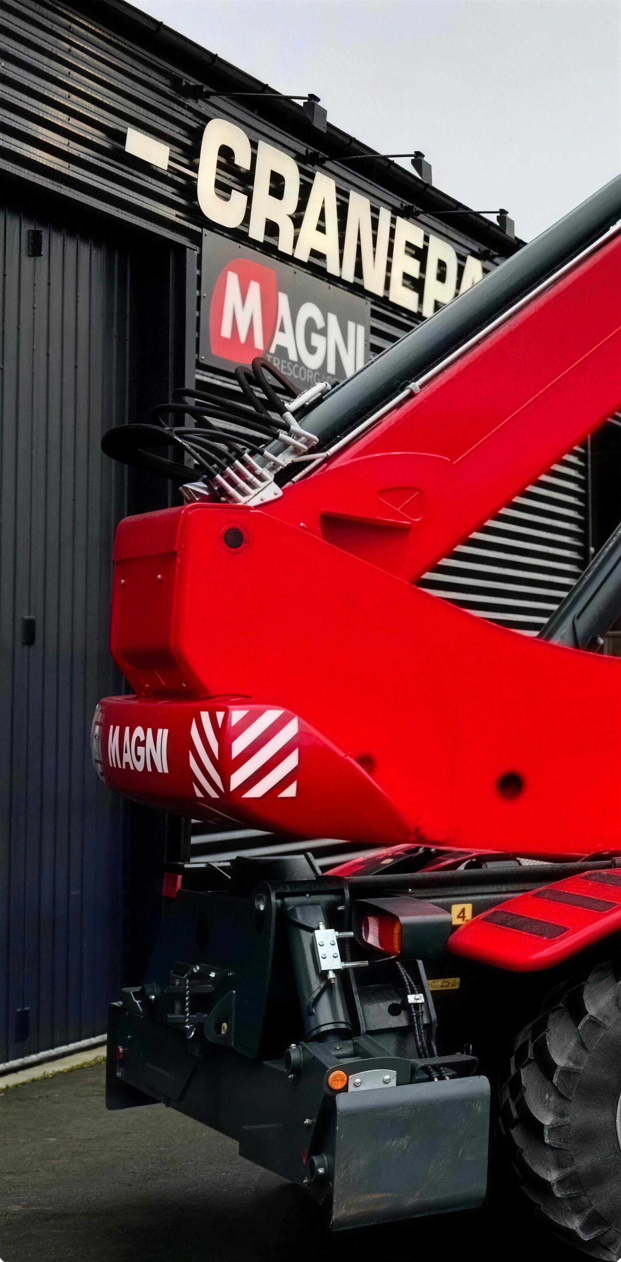Närbild på en röd Magni-maskin framför Cranepartners verkstadsfasad med Magni-skylten.
